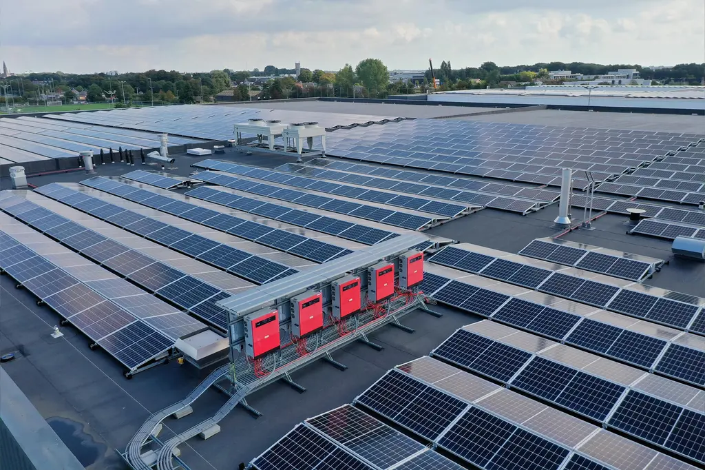 Plat bedrijfsdak vol zonnepanelen met een rij omvormers